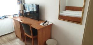 Habitación con escritorio, TV y espejo. en Hotel Gaya, en Bad Soden am Taunus