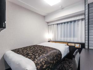 a small room with a bed and a window at APA Hotel Shin Osaka Ekimae in Osaka