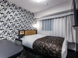 a bedroom with a bed with a patterned wall at APA Hotel Shin Osaka Ekimae in Osaka
