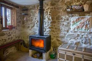 a stove in a room with a stone wall at El Pajar de Tía María in Casas del Castañar