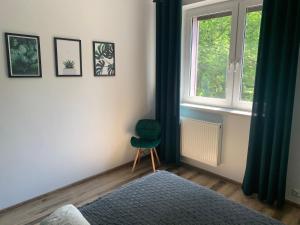 a bedroom with a green chair and a window at Apartament z widokiem Tarnowskie Góry in Tarnowskie Góry