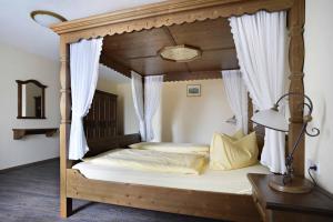 Hotel und Restaurant Rittergut Kreipitzsch في ناومبورغ: غرفة نوم مع سرير مظلة مع ستائر بيضاء