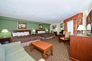 a hotel room with two beds and a living room at Howard Johnson by Wyndham Newark Airport in Newark