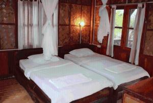 two twin beds in a room with two windows at Sainamhai Resort in Ban Namsanam