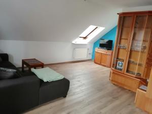 a living room with a black couch and a tv at Ferienwohnung am Riedrain in Eichenzell