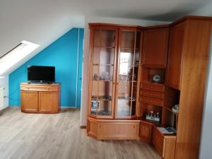 a living room with a wooden cabinet and a television at Ferienwohnung am Riedrain in Eichenzell