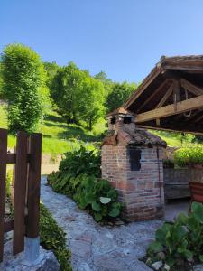 einen Backsteinofen in einem Garten neben einem Holzzaun in der Unterkunft Apartamentos Rurales La Caviana in Cangas de Onís