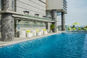 a swimming pool with white chairs and a building at Pullman Saigon Centre in Ho Chi Minh City