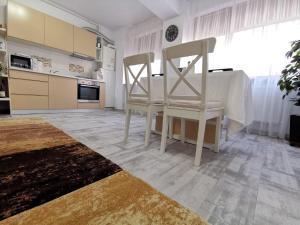 a kitchen with two white chairs and a table at Cappuccino Apartment-Brilliant Apartments in Constanţa