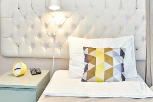 uma cama com uma cabeceira acolchoada branca e uma almofada em Seven Bridges Hotel em São Petersburgo