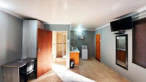 a room with a kitchen and a room with a table at Genesis Self Catering Apartments in Bloemfontein +6 photos
