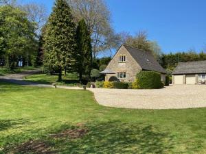 a house with a grass yard and a driveway at Far Hill Cottage in Wyck Rissington