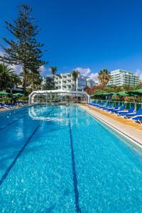 a large swimming pool with blue chairs and a building at Parque Vacacional Eden in Puerto de la Cruz