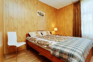 a bedroom with a bed and a white chair at Holiday Home Viktorija B in Jūrmala