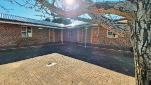 um edifício de tijolos com uma árvore em frente em Genesis Self Catering Apartments em Bloemfontein