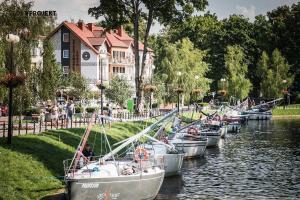 a group of boats docked in a river in front of a building at Apartamenty PORTO in Giżycko