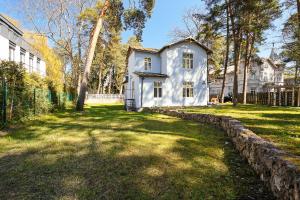a white house with a stone wall in the yard at Holiday Home Viktorija B in Jūrmala