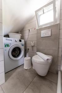 a bathroom with a washing machine and a toilet at Lofos Apartments in Nea Peramos