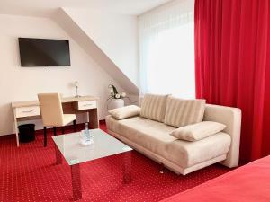 ein Wohnzimmer mit einem Sofa und einem Schreibtisch in der Unterkunft Hanse Hotel in Soest