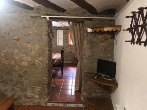a living room with a stone wall and a television at CASA ELISA in Masdenverge