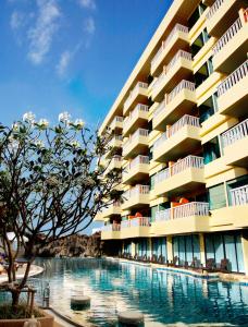 a hotel with a swimming pool in front of a building at Palmyra Patong Resort Phuket - SHA Extra Plus in Patong Beach