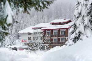 budynek pokryty śniegiem i pokryty śniegiem drzewami w obiekcie Hotel Elitza w mieście Pamporowo