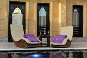 達哈布的住宿－Casa d'Or Dahab PALAZZO，两把椅子,紫色靠垫,坐在游泳池旁