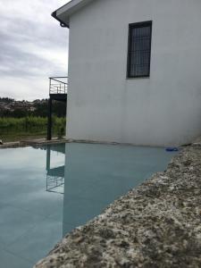 ein weißes Gebäude mit einem Pool mit Wasser daneben. in der Unterkunft Casa Nova in Guimarães