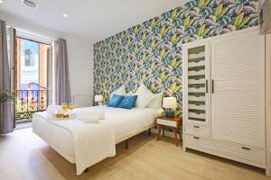 a bedroom with a large white bed with a floral wallpaper at Callao One in Madrid