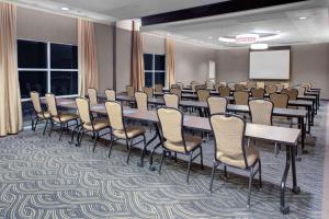 une salle de conférence avec des tables, des chaises et un écran dans l'établissement Hyatt House Raleigh Durham Airport, à Morrisville