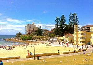a group of people on a beach near the ocean at Guesthouse 83 in Cronulla