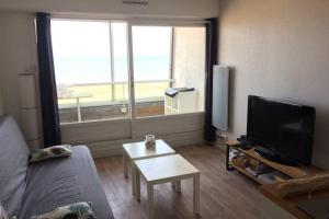 uma sala de estar com um sofá, uma televisão e uma mesa em Appartement T2 avec vue sur mer directe ! em Courseulles-sur-Mer