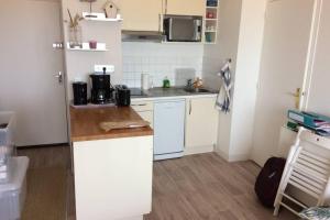 una pequeña cocina con armarios blancos y encimera en Appartement T2 avec vue sur mer directe !, en Courseulles-sur-Mer