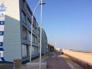 ein Gebäude am Strand neben einem Leuchtturm in der Unterkunft Appartement T2 avec vue sur mer directe ! in Courseulles-sur-Mer