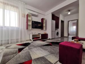 ein Wohnzimmer mit einem TV und einem roten Stuhl in der Unterkunft Violet Apartment-Brilliant Apartments in Constanţa