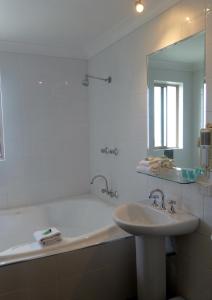 bagno con vasca, lavandino e specchio di Park Ridge Retreat a Gerringong
