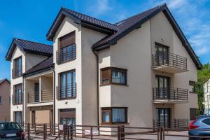 ein weißes Gebäude mit einem schwarzen Dach in der Unterkunft Apartament Margo in Łeba