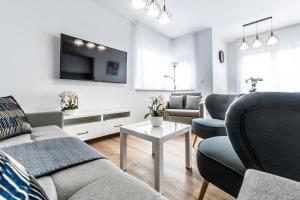 ein Wohnzimmer mit Sofa, Sesseln und Fernseher in der Unterkunft Apartament Margo in Łeba