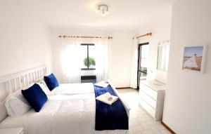 a bedroom with a white bed and blue pillows at T3 Holiday Cottage near the beach | B111 in Porches