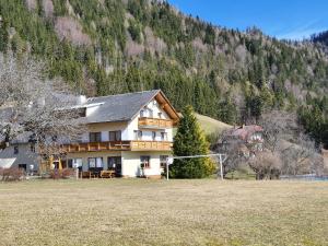 a large house with a field in front of a mountain at Pension Lindbichler in Vorderstoder