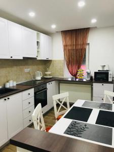 uma cozinha com armários brancos e uma mesa com cadeiras em Comfy apartment em Carei