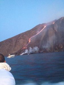 un hombre en un barco mirando un fuego en una montaña en Residence Casa Torretta en Gioiosa Marea