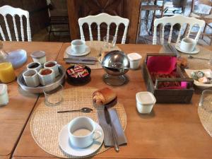 una mesa de madera cubierta con platos y tazas de café en Maison Basta, en Orthevielle