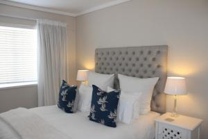 een slaapkamer met een bed met blauwe en witte kussens bij Waterfront - Knysna Quays Accommodation in Knysna
