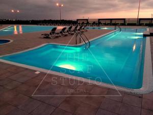 a swimming pool at night with chairs around it at The Surf Studio - Ericeira in Ericeira