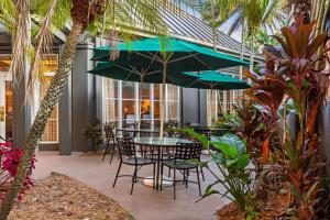 La Quinta by Wyndham Ft. Lauderdale Plantation في بلانتايشن: فناء مع طاولة وكراسي ومظلات
