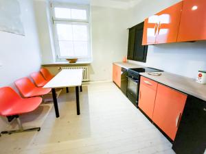 uma cozinha com armários laranja e uma mesa e cadeiras em Alte Schule Gästehaus - Fräulein Apartment em Bitburg
