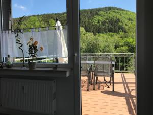 eine offene Tür zu einem Balkon mit Blick auf einen Tisch in der Unterkunft Haus Kyllblick in Birresborn