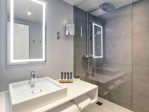 a bathroom with a white sink and a shower at Novotel Poznan Centrum in Poznań