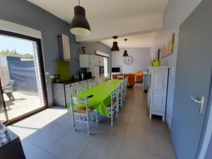 a kitchen and dining room with a green table and chairs at CLOS DE L'OCEAN 2 - maison 3 chambres à 300 m de la plage in Saint-Jean-de-Monts